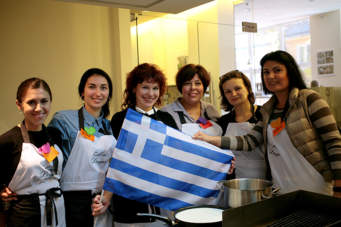 Participants and greek flag. Greek cuisine dishes. Cooking school in Ukraine.